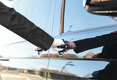 Chauffeur avec des gants blancs ouvrant la portière à son client