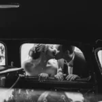 Mariés s'embrasant près d'une voiture