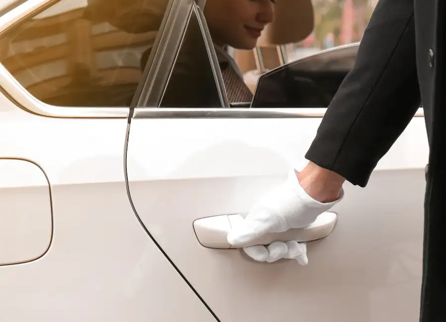 homme avec des gants ouvrant la portière d'une voiture blanche